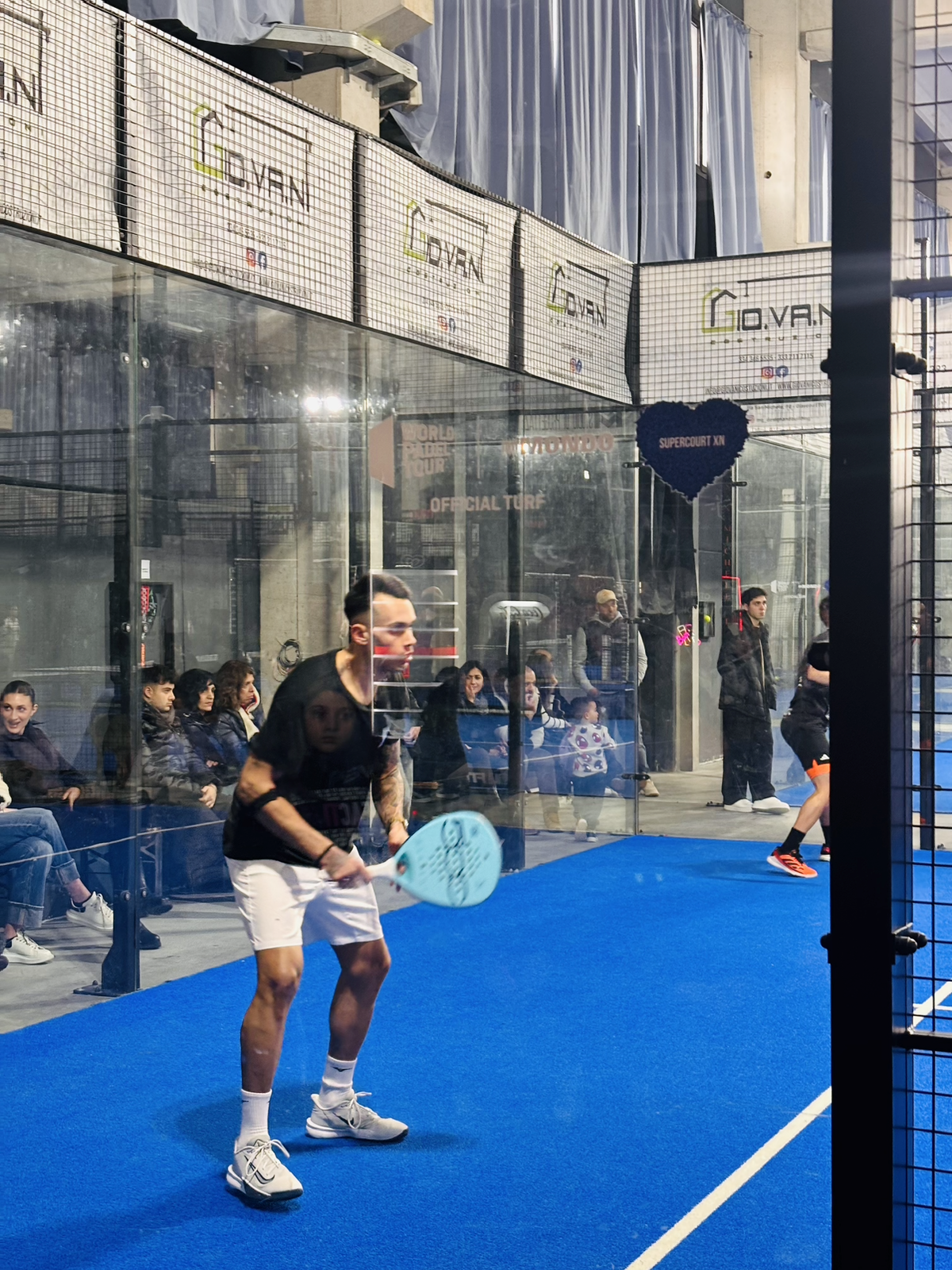 Giocatore con racchetta sul campo blu indoor del San Michele Padel Club